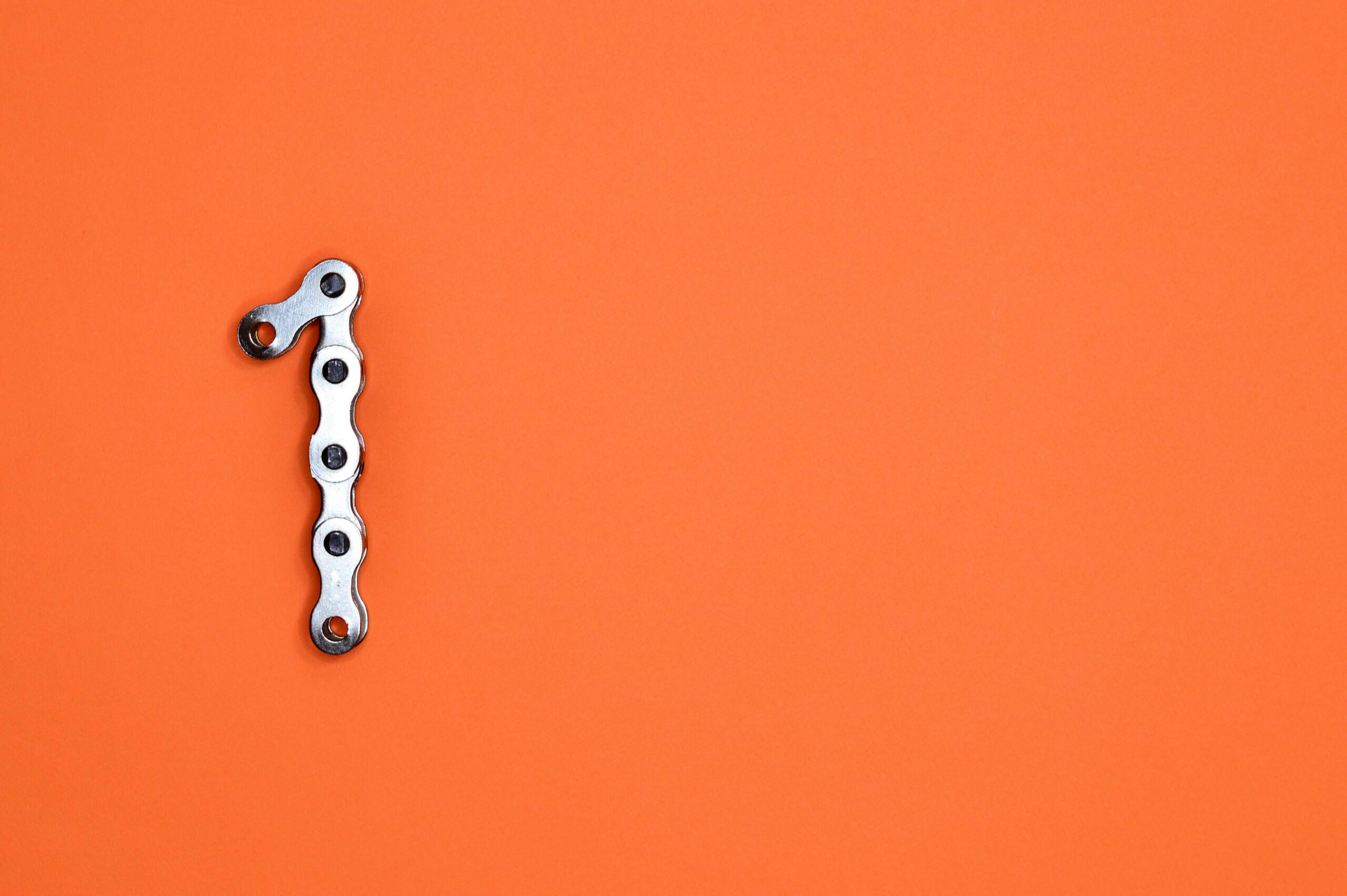 الصفحة الرئيسية Metal chain forming the number one on an orange background, ideal for design concepts.